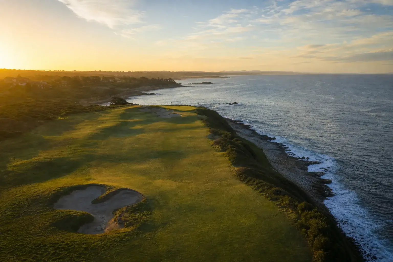 Golf en bord de mer vu du ciel au lever du jour, les fairways déserts, aucune présence humaine sur le parcours.