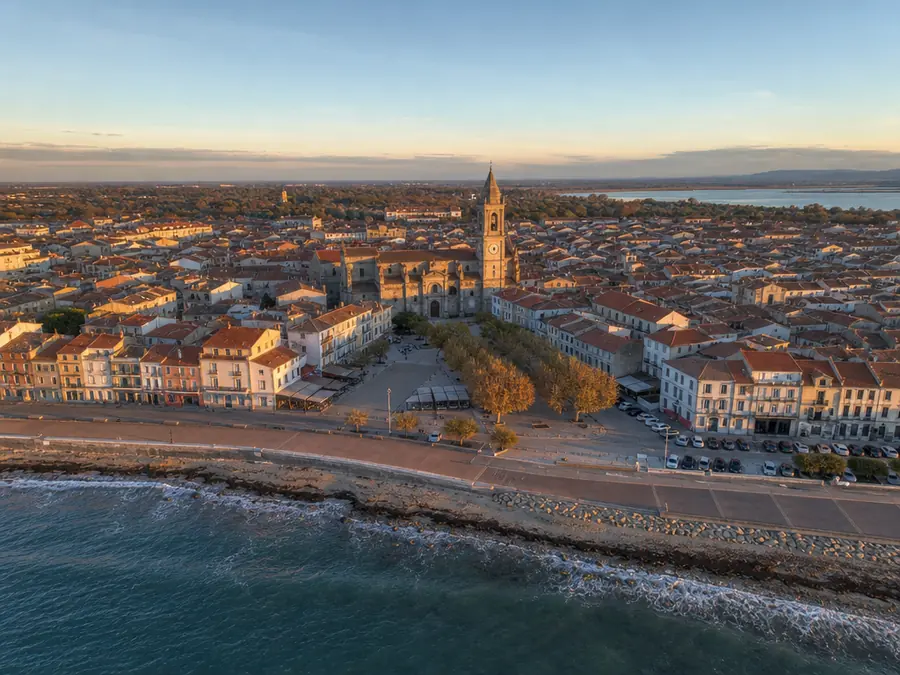 Petite ville côtière vue du ciel : clocher, place de marché, toits de tuiles et promenade de front de mer.