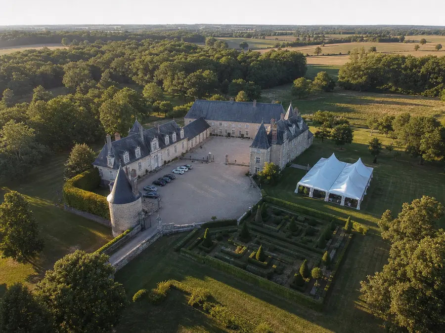 Château de réception vu du ciel : chapiteau blanc monté sur la pelouse, jardins à la française et cour de gravier.